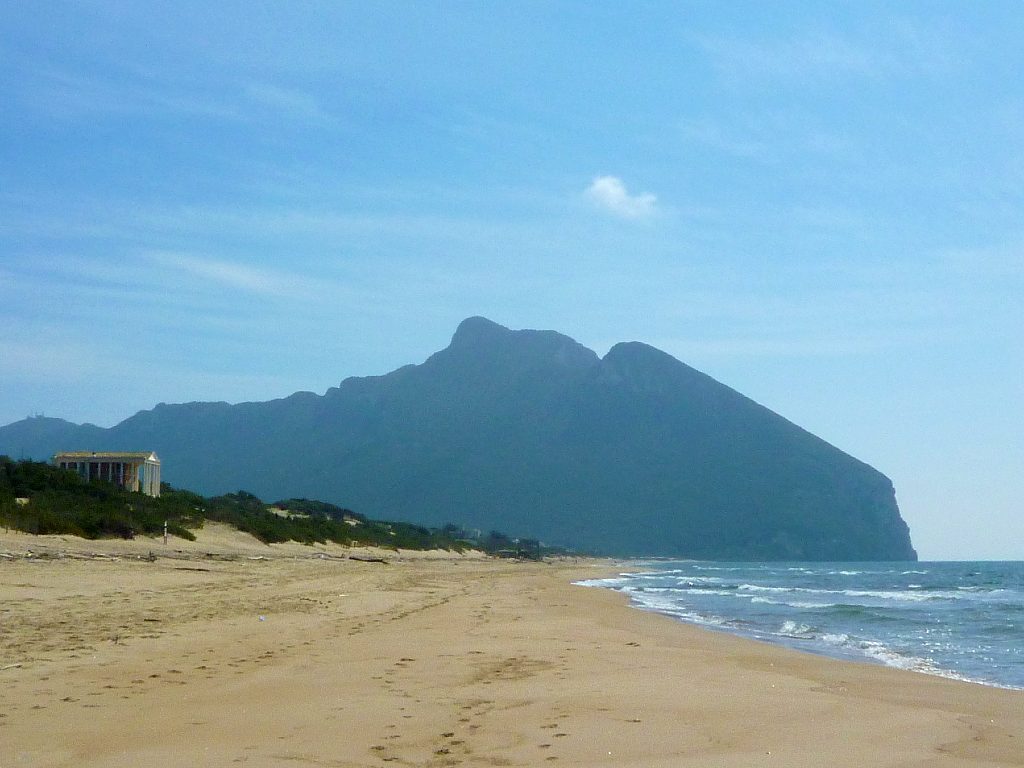 La spiaggia di Sabaudia tra il mar Tirreno e il cordone dunale ricco di vegetazione, che la delimita alla spalle. Sullo sfondo spicca il Promontorio del Circeo che segna il limite sud della spiaggia di Sabaudia.