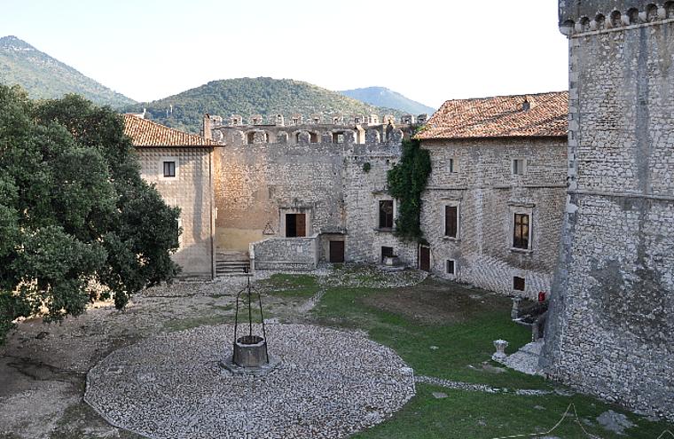Castello di Sermoneta, vista parziale del Mastio e dell'edificio della Sala dei Baroni, dalla Piazza d'Armi. Al centro della Piazza d'Armi, la cisterna.